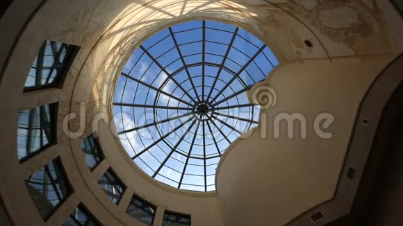 透过现代建筑天花板上的圆形玻璃窗的移动的云彩和阳光的景色视频的预览图