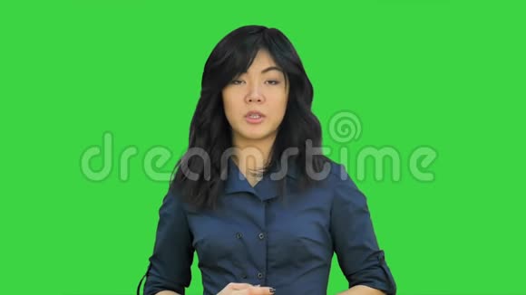 穿着蓝色西装的女商人微笑着看着镜头在绿色屏幕上用手势解释Chroma键视频的预览图