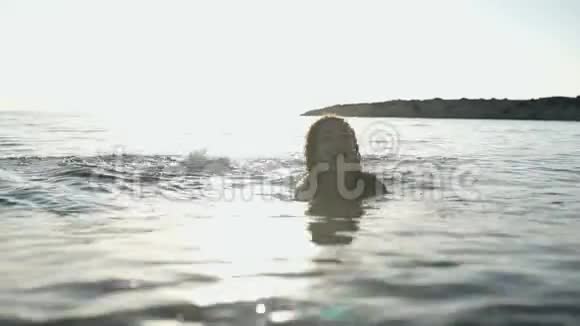 可爱的女孩在日落的背景下在海边放松视频的预览图