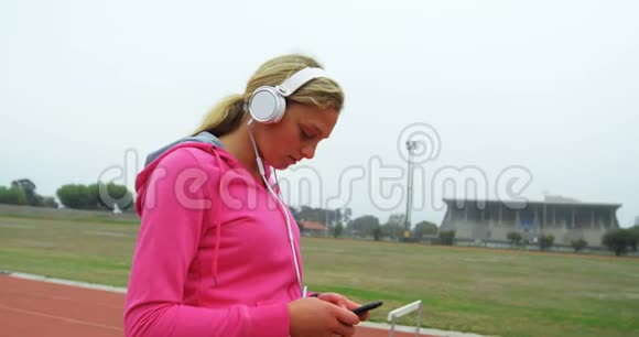 女子运动员在4k体育场地听手机音乐视频的预览图