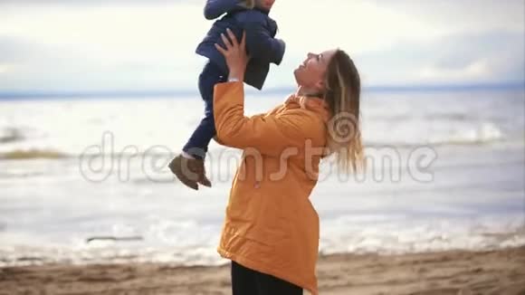 一位年轻的母亲在海滩上玩她的孩子她把她的儿子扔了出去视频的预览图