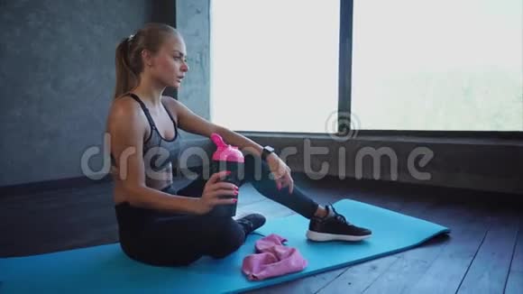 漂亮健康的女人坐在运动垫上锻炼后休息视频的预览图