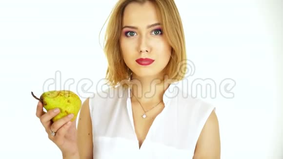 一个年轻的女人从梨子里咬了一口白底视频视频的预览图
