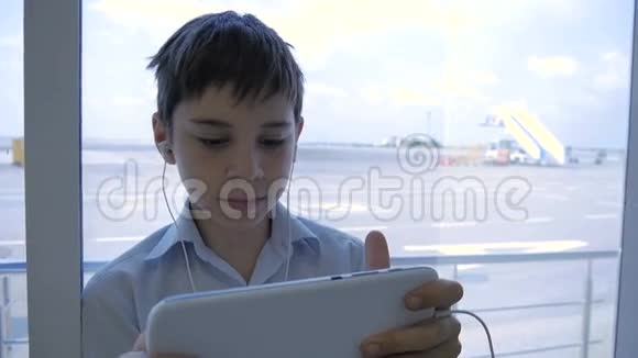 在机场的那个男孩在平板电脑上玩视频的预览图
