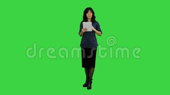 亚洲女人看着相机说话拿着绿色屏幕上的数字平板电脑Chroma键视频的预览图