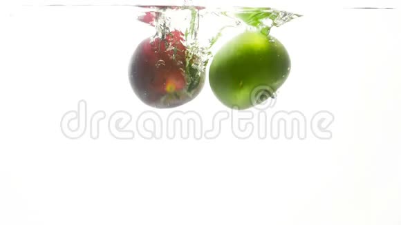 近景慢动作视频新鲜的绿红苹果在冷水中白色背景下坠落视频的预览图