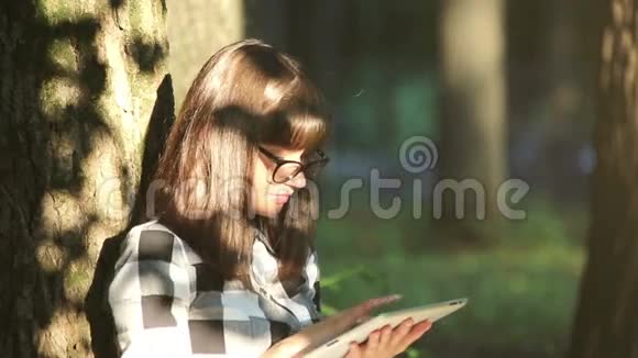 女孩正在公园里用平板电脑放松视频的预览图