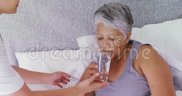 女医生在4k床上给生病的老年妇女一杯水视频的预览图