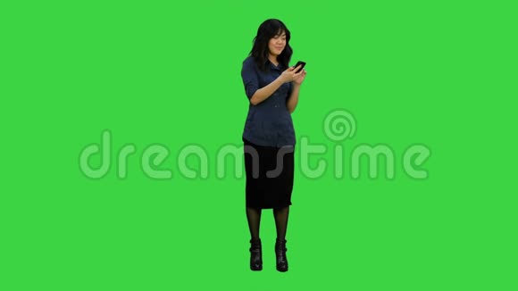 美丽的亚洲女孩有智能手机唱歌和跳舞同时在绿色屏幕上听音乐Chroma键视频的预览图