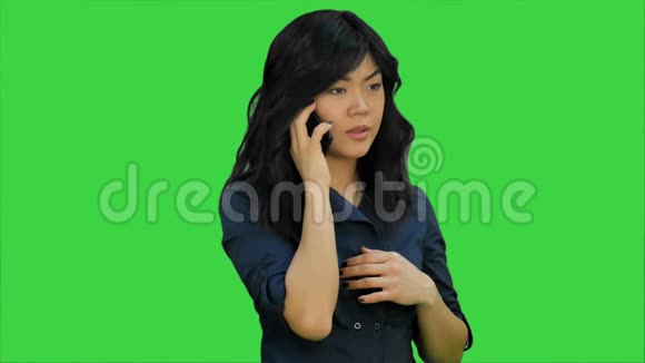穿蓝色西装的女商人在绿色屏幕上用手机说话Chroma键视频的预览图