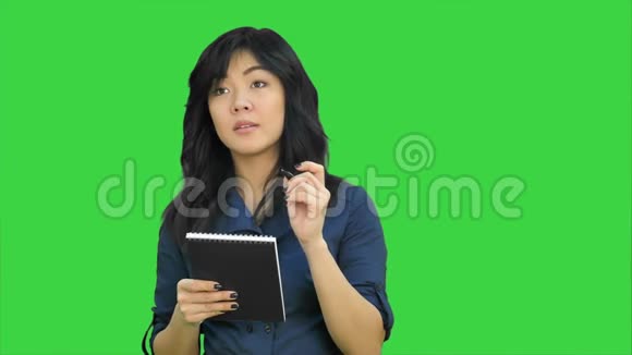 有魅力的亚洲女孩在绿色屏幕上写下笔记Chroma键视频的预览图