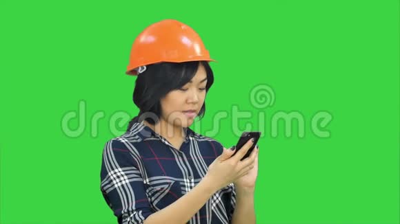 带橙色头盔的女建筑师使用绿色屏幕上的智能手机Chroma键视频的预览图