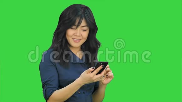 积极的年轻美丽的亚洲女人使用手机跳舞和微笑的绿色屏幕Chroma键视频的预览图