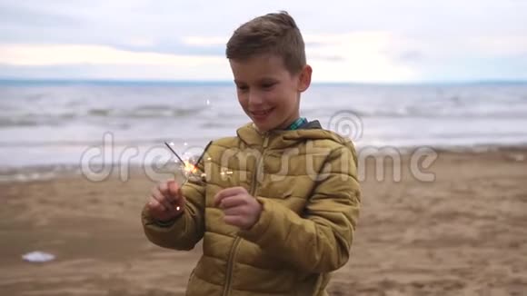 一个快乐的孩子在海滩上玩孟加拉灯他想把它们熄灭视频的预览图