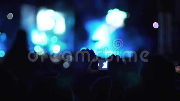 男子手举着智能手机在空中拍摄音乐会气氛的视频视频的预览图