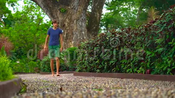 一个年轻人在热带公园的反射路径上慢镜头视频的预览图