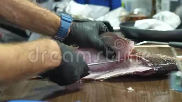 男人戴着黑手套的手把鱼片剪掉视频的预览图