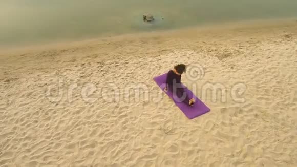 从Drone的空中俯瞰一个年轻的女孩在河边练习瑜伽视频的预览图