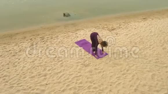 从Drone的空中俯瞰一个年轻的女孩在河边练习瑜伽视频的预览图