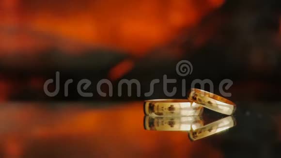 静态框架两个金环靠火从壁炉玻璃桌黑色深色背景视频的预览图