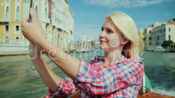 年轻女子拍摄意大利威尼斯美丽景色的照片她在大运河游船上航行视频的预览图