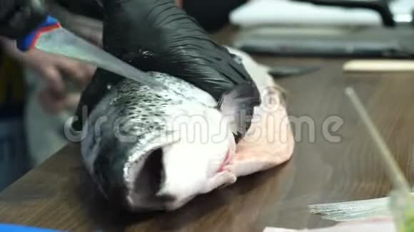 男人戴着黑色手套的手砍掉了鱼的头视频的预览图