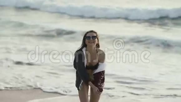 戴墨镜的快乐女孩在海边的沙滩上嬉戏视频的预览图