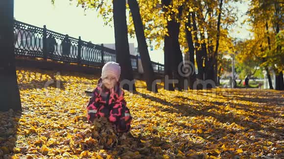印度夏天小可爱的女孩在城市公园里玩黄叶视频的预览图