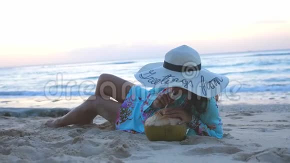 年轻的游客微笑着戴着太阳镜和帽子的美女躺在热带天堂沙滩上喝着饮料视频的预览图