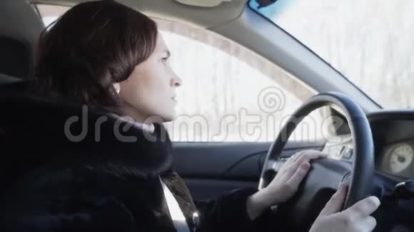 一个穿着黑色皮毛大衣的女人正在开车视频的预览图