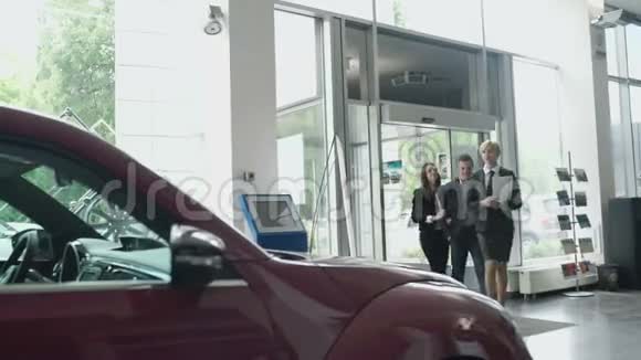 经理和汽车经销店里的一对年轻夫妇谈论汽车视频的预览图