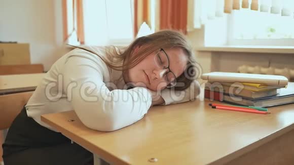 那个戴着眼镜睡在班上书上的疲倦的学生女孩视频的预览图