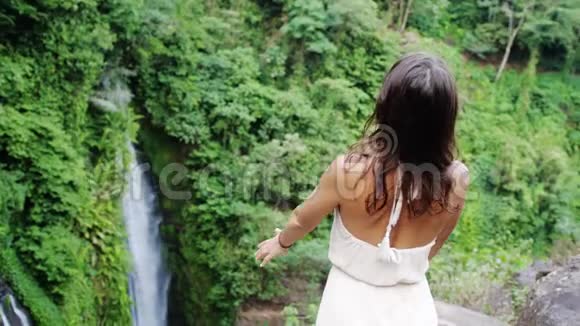穿着长裙的年轻黑发女子在丛林苏梅岛的瀑布前举手泰国慢动作3840x2160视频的预览图