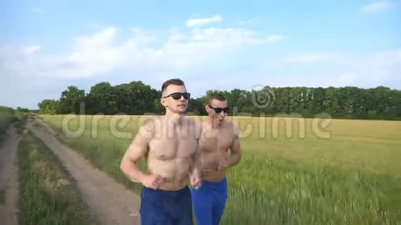 两个肌肉发达的男人在户外跑步和交谈年轻的微笑运动员在球场上慢跑男运动员视频的预览图