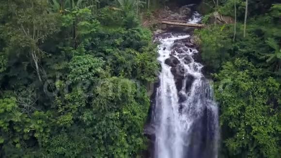 在美丽的巴厘岛天堂瀑布和热带雨林的亚洲旅行中空中起重机的风格随着无人机的倾斜而下降视频的预览图