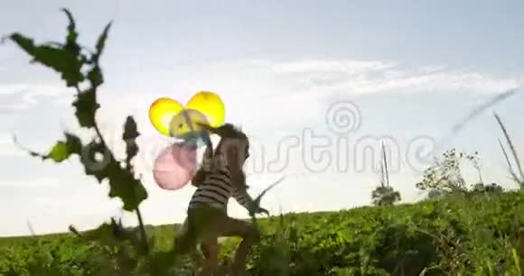 日落时分在绿茵场上用气球慢跑和奔跑的小女孩视频的预览图