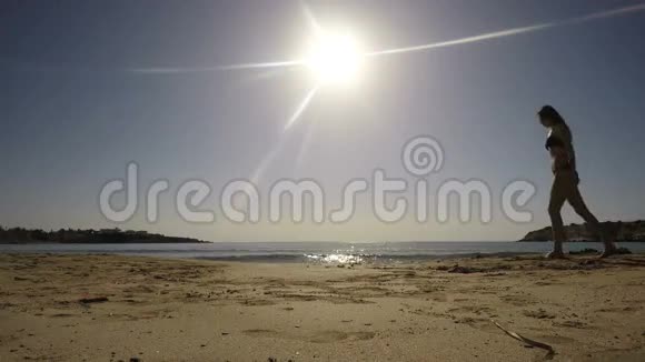 年轻的黑发戴着太阳镜在海边散步视频的预览图