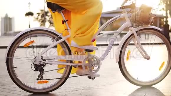 白色城市自行车车轮旋转的特写镜头有铃铛篮子和花的城市自行车无法辨认的妇女视频的预览图