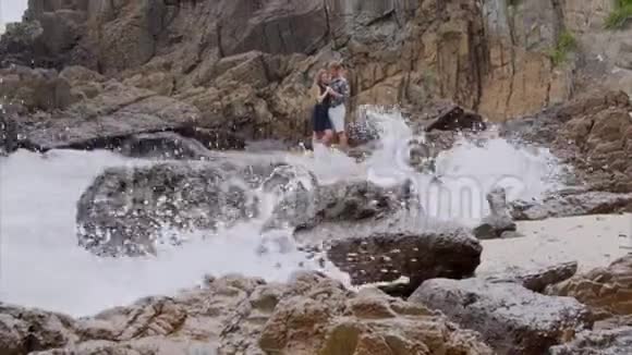 年轻夫妇在海滨拥抱和亲吻美丽的海景和海浪视频的预览图