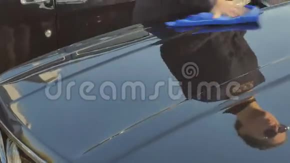 戴墨镜的漂亮卷发女孩清洁了一辆老式汽车的引擎盖视频的预览图