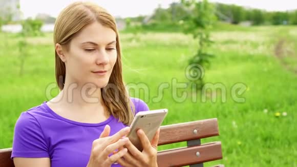 公园里的慢动作女人在手机上发短信使用她的智能手机和朋友聊天视频的预览图
