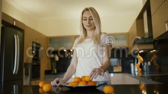漂亮的金发女郎在厨房里用橘子做金字塔视频的预览图