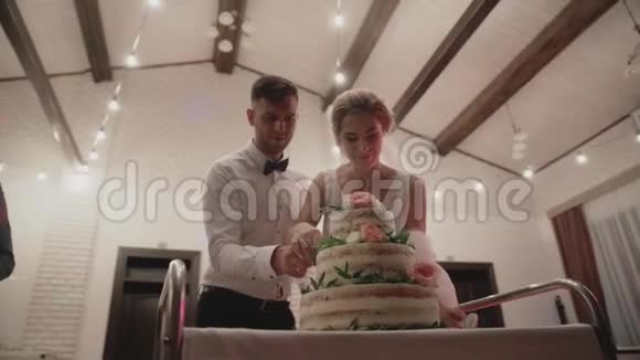幸福的新娘和新郎切婚礼蛋糕装饰鲜花的婚礼蛋糕视频的预览图