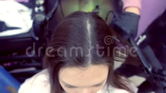 美容师在美容院用发钳给美女扎黑棕色头发视频的预览图