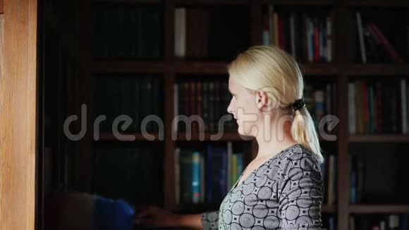 侧视女人用书去除书架上的灰尘用刷子刷灰尘打扫房子视频的预览图
