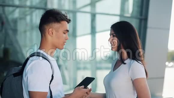 美丽可爱的情侣站在机场或火车站附近他们用智能手机指着她的手指视频的预览图