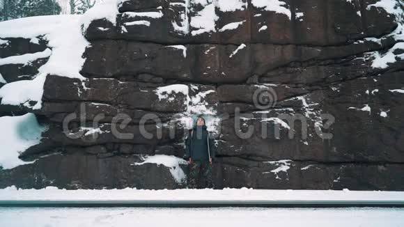 年轻人在白雪覆盖的石山墙前沉思视频的预览图