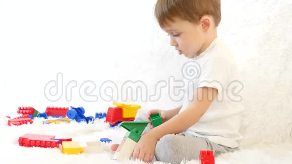 快乐的孩子坐在沙发上在彩色的积木里玩耍坐在白色的背景上视频的预览图