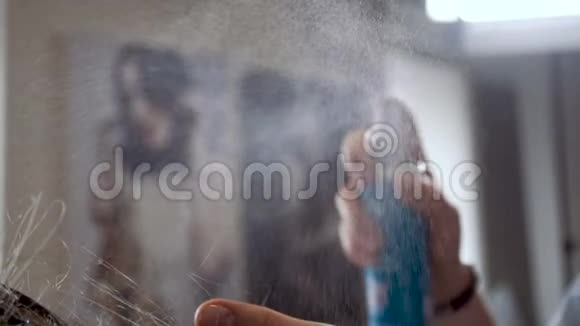 在发型师的手中喷洒喷雾剂用慢速处理金发视频的预览图