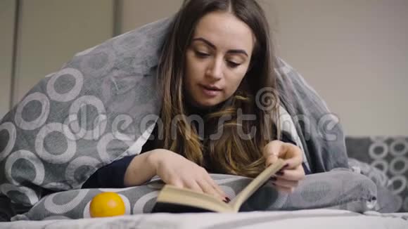 年轻漂亮的女人躺在床上她在放松看书视频的预览图